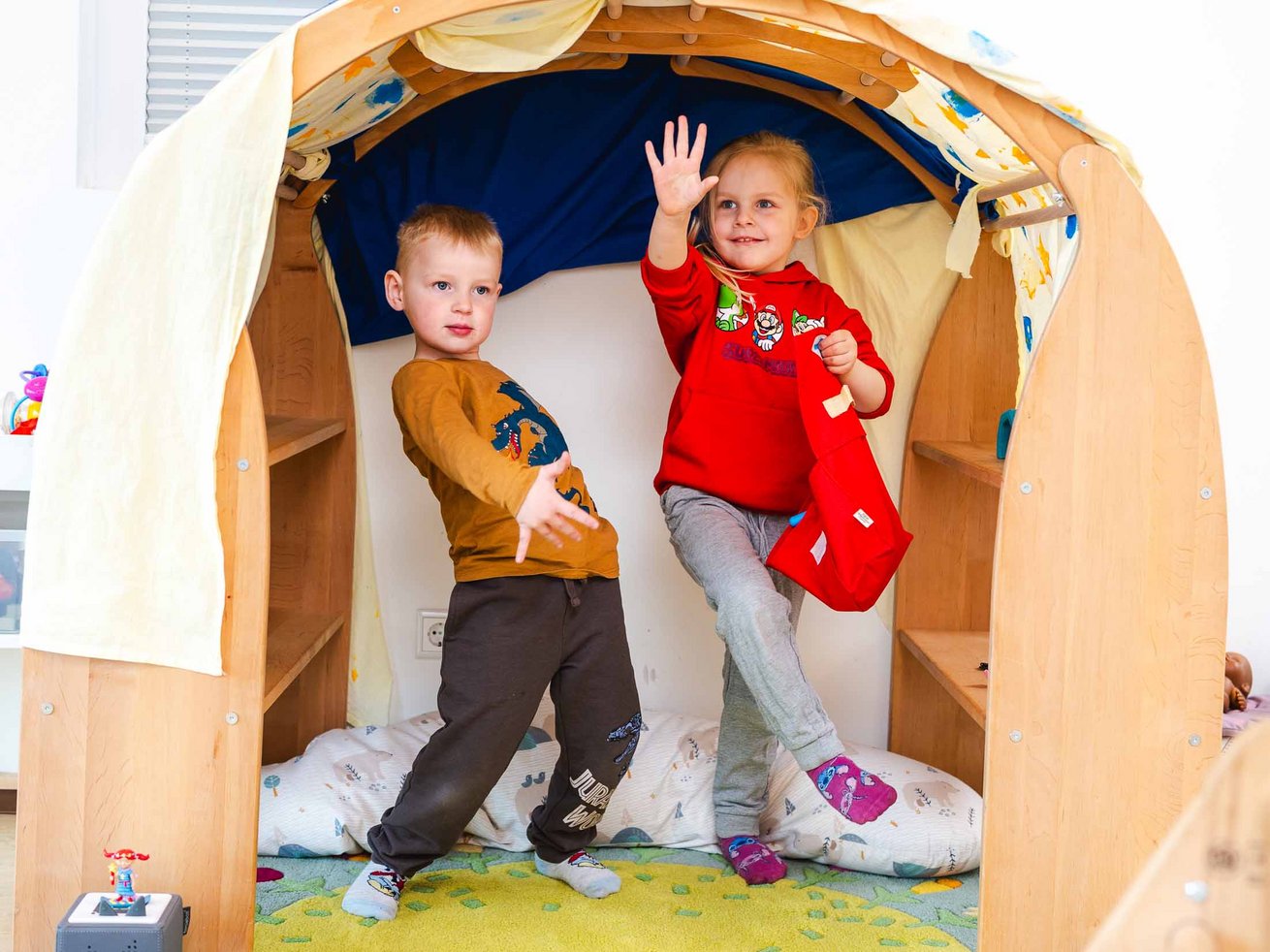 Zwei Kinder spielen gemeinsam in einer Spielhöhle aus Holz in der Kita Anne-Frank-Ring.