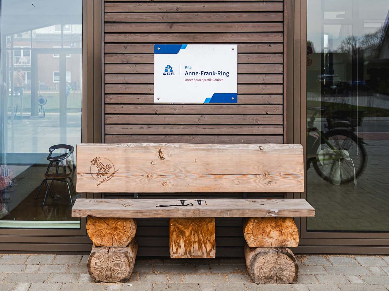 Eingangsbereich der Kita Anne-Frank-Ring in Handewitt mit Holzbank und Kita-Schild.