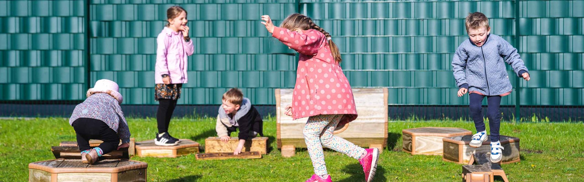 Mehrere Kinder klettern auf einem Parcours, der im Außengelände der ADS-Kita aufgebaut wurde.