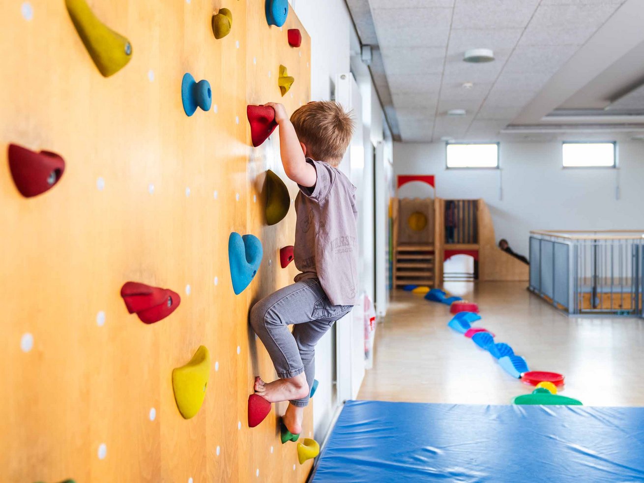 Junge klettert an einer Kletterwand im Bewegungsbereich der Kita.